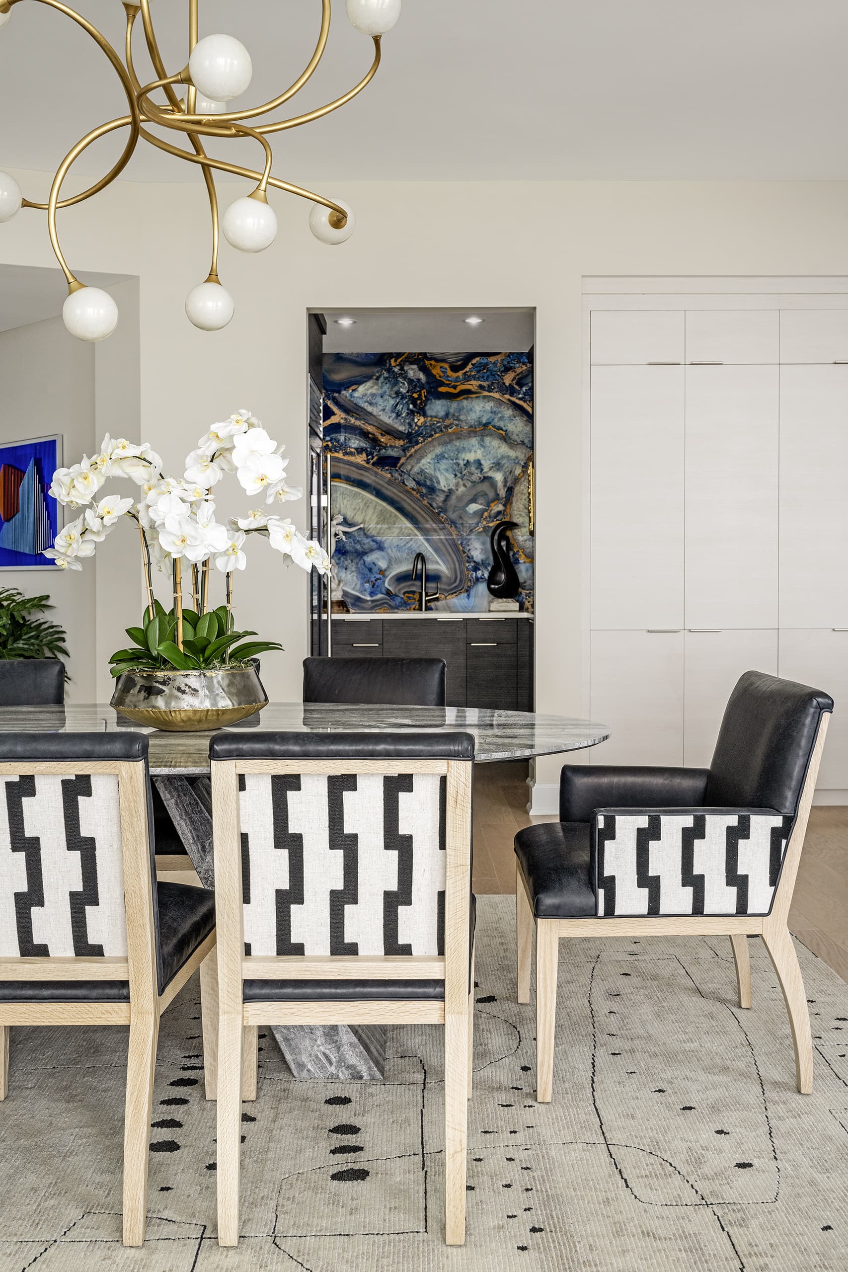 Dining Black Leather Chairs With Black And White Pattern Back White Orchids Wet Bar In The Background