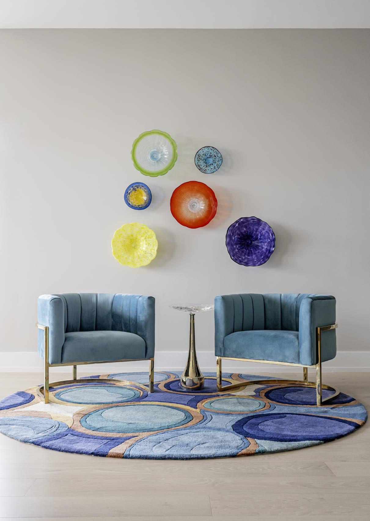 Turquois Blue Suede Armchairs With Gold Frame Colourful Glass Wall Displays Grey Painted Wall