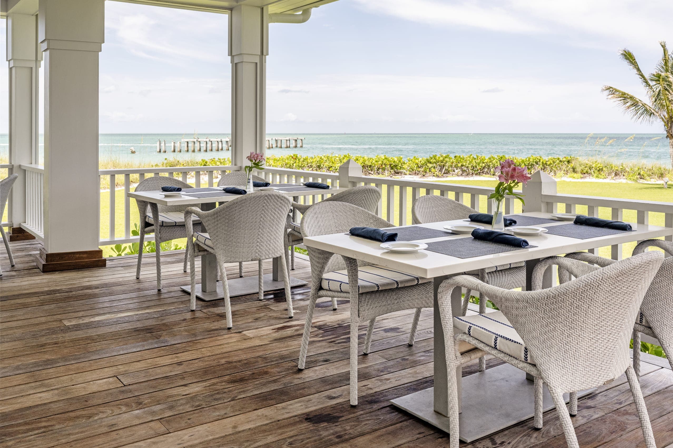 White Wicker Chairs Outside Dining Table Dark Blue Napkin Boca Grande Sea View