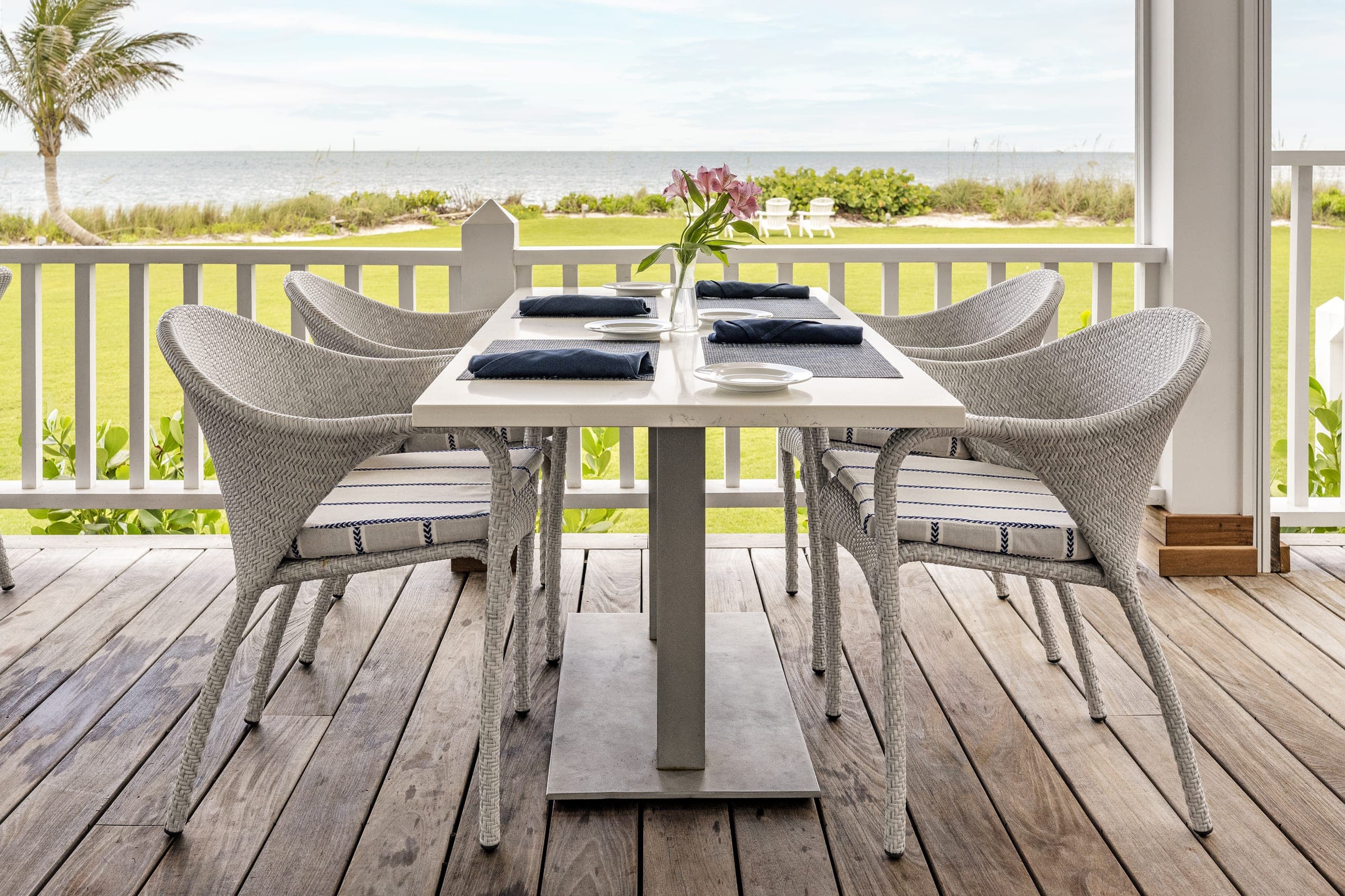 White Wicker Chairs Outside Dining Table Dark Blue Napkin Sea View