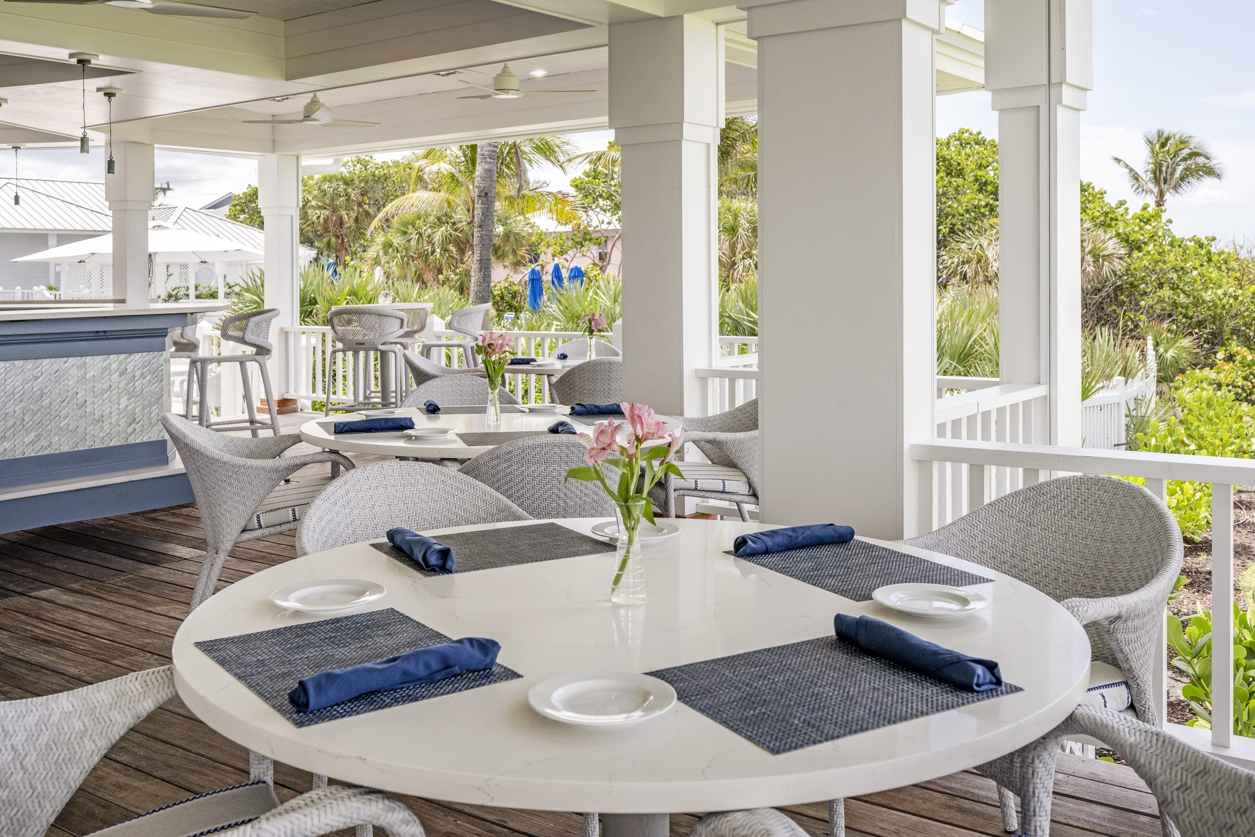 White Wicker Chairs Outside Dining Table Dark Blue Napkin Tropical Palm Trees